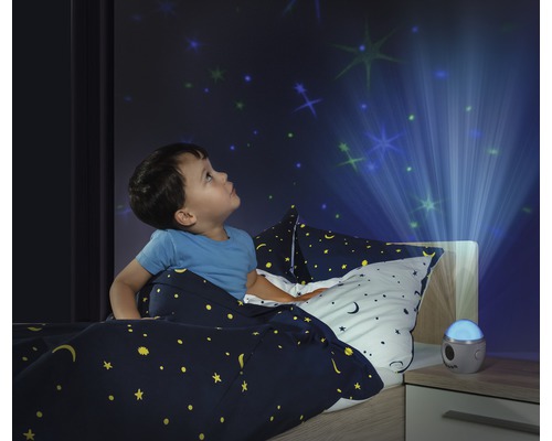 Junge im Bett betrachtet einen Sternenhimmel Projektor an der Wand.
