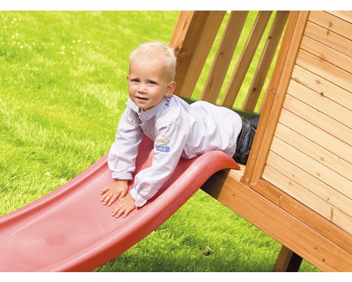 Kind rutscht auf einer Rutsche eines Spielhauses im Garten