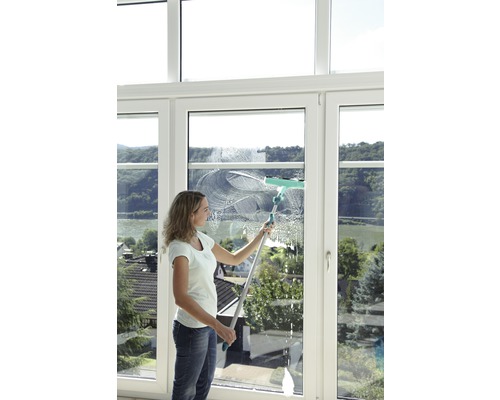 Eine Frau putzt ein Fenster mit einem Fensterwischer.