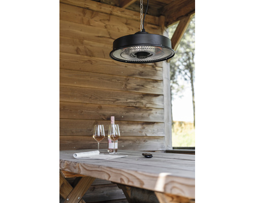 Szene mit einem Deckenheizstrahler über einem Holztisch mit Wein und Zeitung in einem Gartenhaus