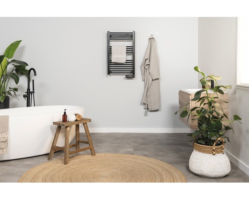 Helles Badezimmer mit Badewanne, Waschtisch, Handtuchwärmer und Zimmerpflanzen für eine freundliche Atmosphäre