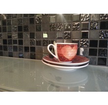 Tasse mit Untertasse auf einem Tisch vor einer Mosaikwand