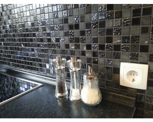 Mosaikfliesenwand in Küche mit Gewürzstreuern und Steckdose