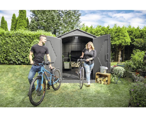 Gartenszene mit Gerätehaus, Fahrrädern und zwei Personen