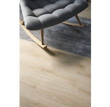 Detailaufnahme eines grauen Schaukelstuhls auf einem Bodenbelag in Holzoptik und Betonoptik.
