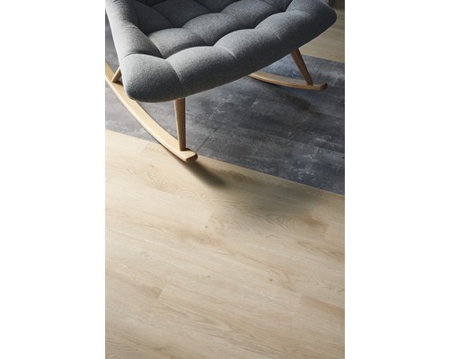 Detailaufnahme eines grauen Schaukelstuhls auf einem Bodenbelag in Holzoptik und Betonoptik.