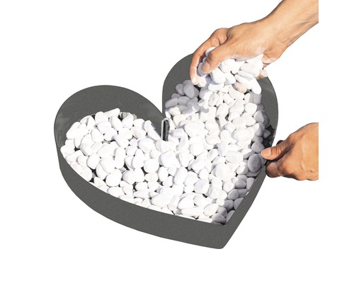 Herzförmige Feuerschale wird mit weißen Steinen befüllt