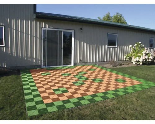 Verlegte Terrassenfliesen auf einer Rasenfläche vor einem Haus.