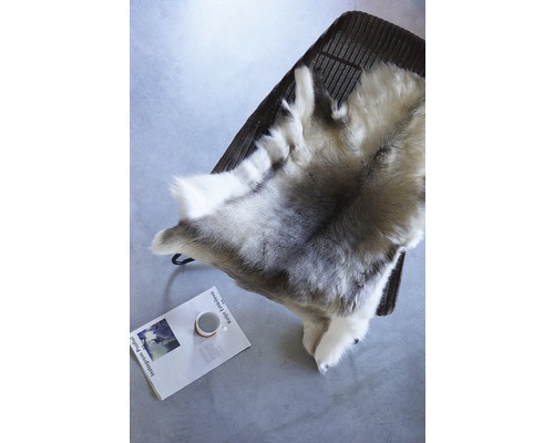 Dekofell auf einem Stuhl, darunter eine Zeitschrift und eine Tasse