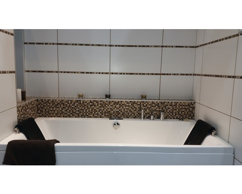 Badezimmer mit Badewanne, Fliesenwand und dekorativen Elementen