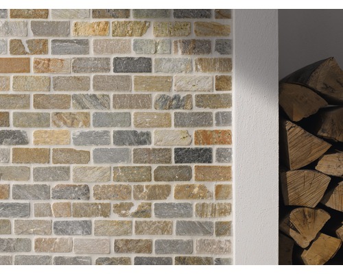 Wand mit Verblendern in Steinoptik und Holzstapel