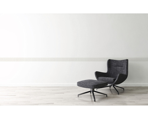 Modernes Interieur mit Sessel und Fußhocker auf hellem Holzboden vor weißer Wand