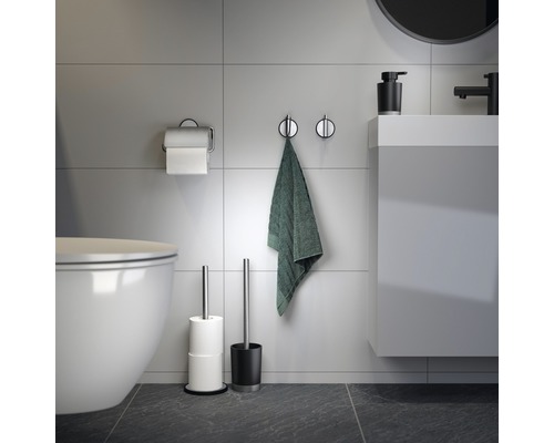 Badezimmer mit Toilette, Handtuch, Toilettenpapierhalter, Toilettenbürste und Waschbecken