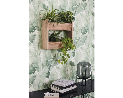 Wandregal aus Holz mit Pflanzen vor einer Tapete mit Blattmuster