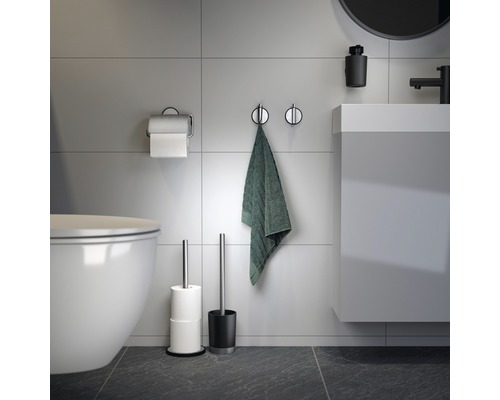 Badezimmer mit Toilette, Waschbecken, Handtuch, Toilettenpapierhalter und WC-Bürste