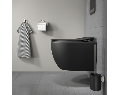 Wandhängendes WC in einem Badezimmer mit Handtuch, Toilettenpapierhalter und WC-Bürste