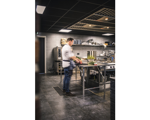 Professionelle Küche mit Koch bei der Zubereitung von Speisen an Edelstahltischen