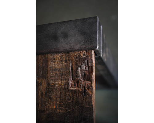 Detailansicht eines Tisches mit Tischplatte aus Metall und Tischbein aus Holz