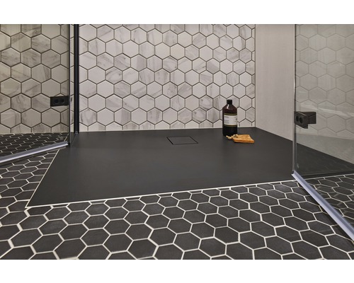 Duschbereich mit flacher, schwarzer Duschwanne und hexagonalen Fliesen an Boden und Wand