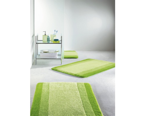 Modernes Badezimmer mit grünen Badteppichen und einem Regal mit Badutensilien.