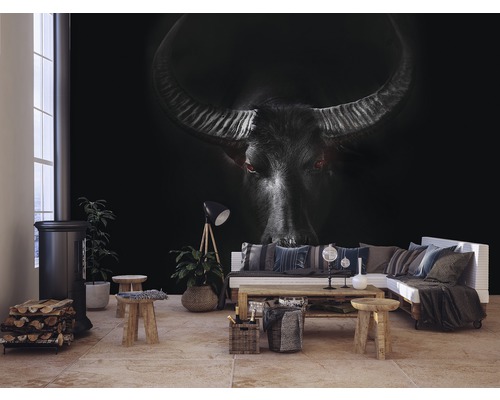 Wohnzimmer mit Fototapete eines Büffels, Kaminofen, Holzscheiten und Couch