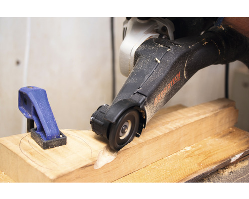 Ein Elektrowerkzeug mit Trennscheibe bearbeitet ein Holzstück, das mit einer Klemme fixiert ist.