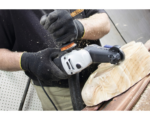 Eine Person schleift ein Holzstück mit einem Elektrowerkzeug. Späne fliegen.