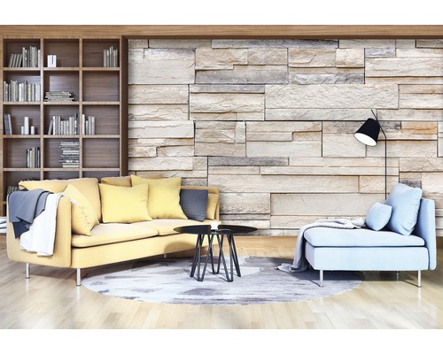 Wohnzimmer mit Bücherregal, Sofa, Sessel, Tisch, Stehlampe und Steinwand