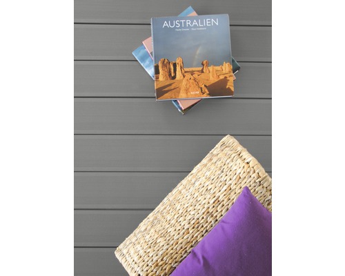 Szene mit Buch, Kissen und Flechtkorb auf Terrassendielen