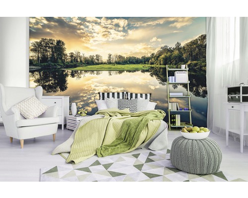 Schlafzimmer mit Fototapete eines Sees bei Sonnenuntergang, Sessel, Bett, Teppich und Beistelltisch