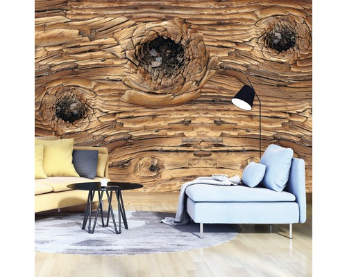 Wohnzimmer mit Fototapete in Holzoptik, Sofa, Sessel, Teppich und Stehlampe.