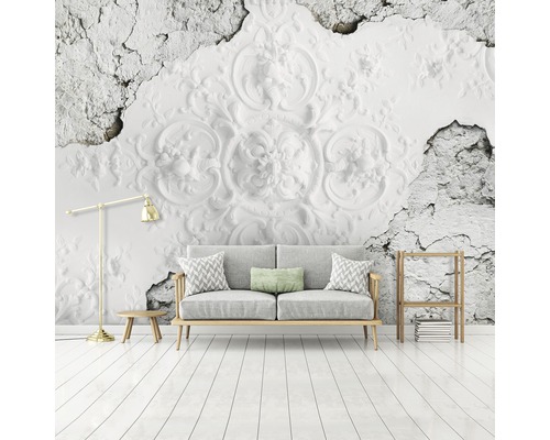 Wohnzimmer mit dekorativer Wandtapete im Stuckdesign hinter einem grauen Sofa