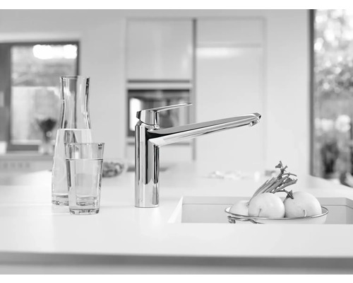 Küchenszene mit Spültischarmatur, Glas und Karaffe