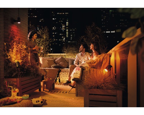Atmosphärische Dachterrasse mit Außenleuchten und entspannten Menschen bei Nacht.