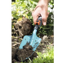 Person pflanzt mit einer Handschaufel in Erde im Garten