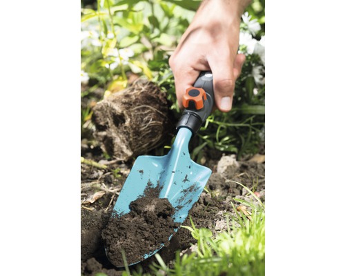 Person pflanzt mit einer Handschaufel in Erde im Garten