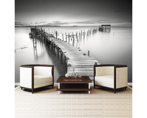 Wohnzimmer mit Fototapete einer Seebrücke, zwei Sesseln und einem Couchtisch
