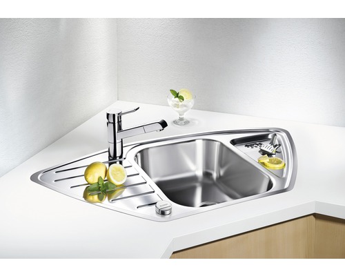 Eckspüle aus Edelstahl mit Armatur und Abtropffläche auf einer Küchentheke.