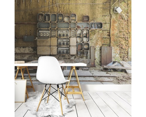 Wohnraum mit Fototapete, die eine alte Schalttafel und eine baufällige Wand darstellt, dazu ein weißer Schreibtisch und ein Stuhl.