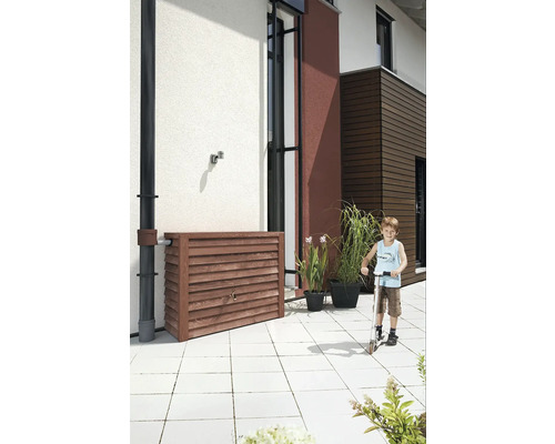 Holzregentonne zur Gartenbewässerung mit Kind auf Tretroller vor Hauswand