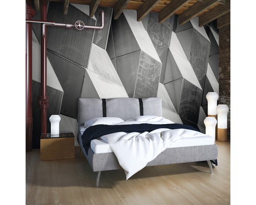 Schlafzimmer mit graublauem Bett vor einer geometrischen Tapete