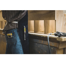 Handwerker mit Maßband, Arbeitsleuchte und Druckluftnagler bei der Arbeit mit Holz