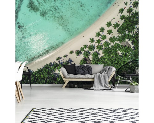 Wohnzimmer mit Fototapete, die einen Strand mit Palmen von oben zeigt