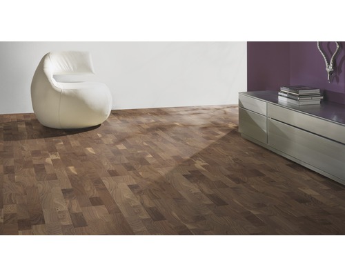 Raumansicht mit Holzparkettboden, Sessel und Kommode