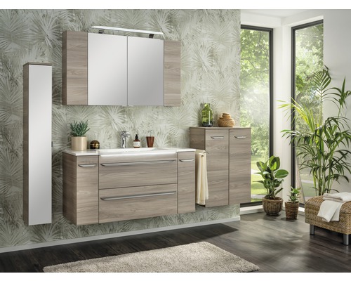 Modernes Badezimmer mit Waschtisch, Spiegelschrank und Hochschrank in Holzoptik vor einer Wand mit Pflanzenmuster.