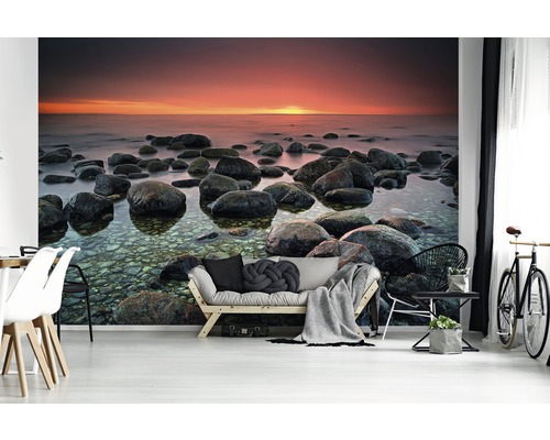 Wohnraum mit Fototapete eines Steinstrandes bei Sonnenuntergang