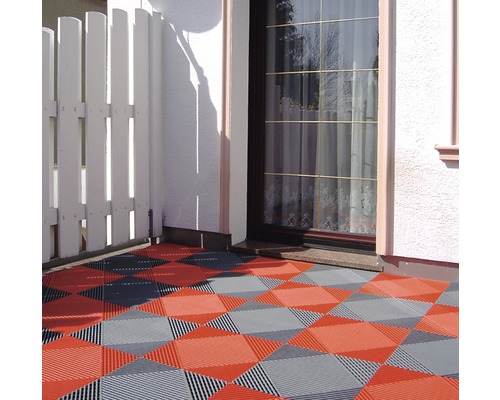 Terrasse mit Kunststofffliesen in Rot und Grau vor einem Haus
