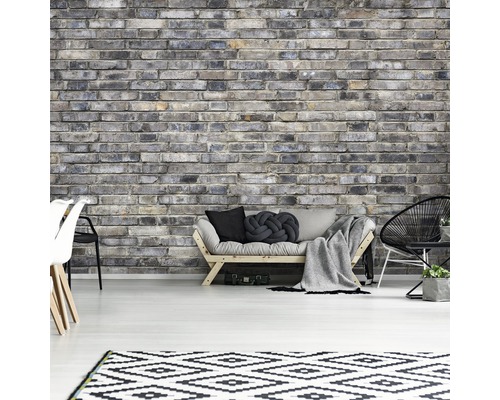 Wohnzimmer mit grauer Backsteinwand, Sofa, Teppich und Stühlen