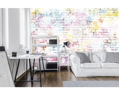 Büro mit Schreibtisch, Regal und Sofa vor einer farbenfrohen Backsteintapete