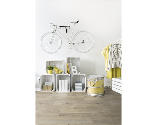 Dekoratives Zimmer mit Fahrrad an der Wand, Holzkisten und Laminatboden.